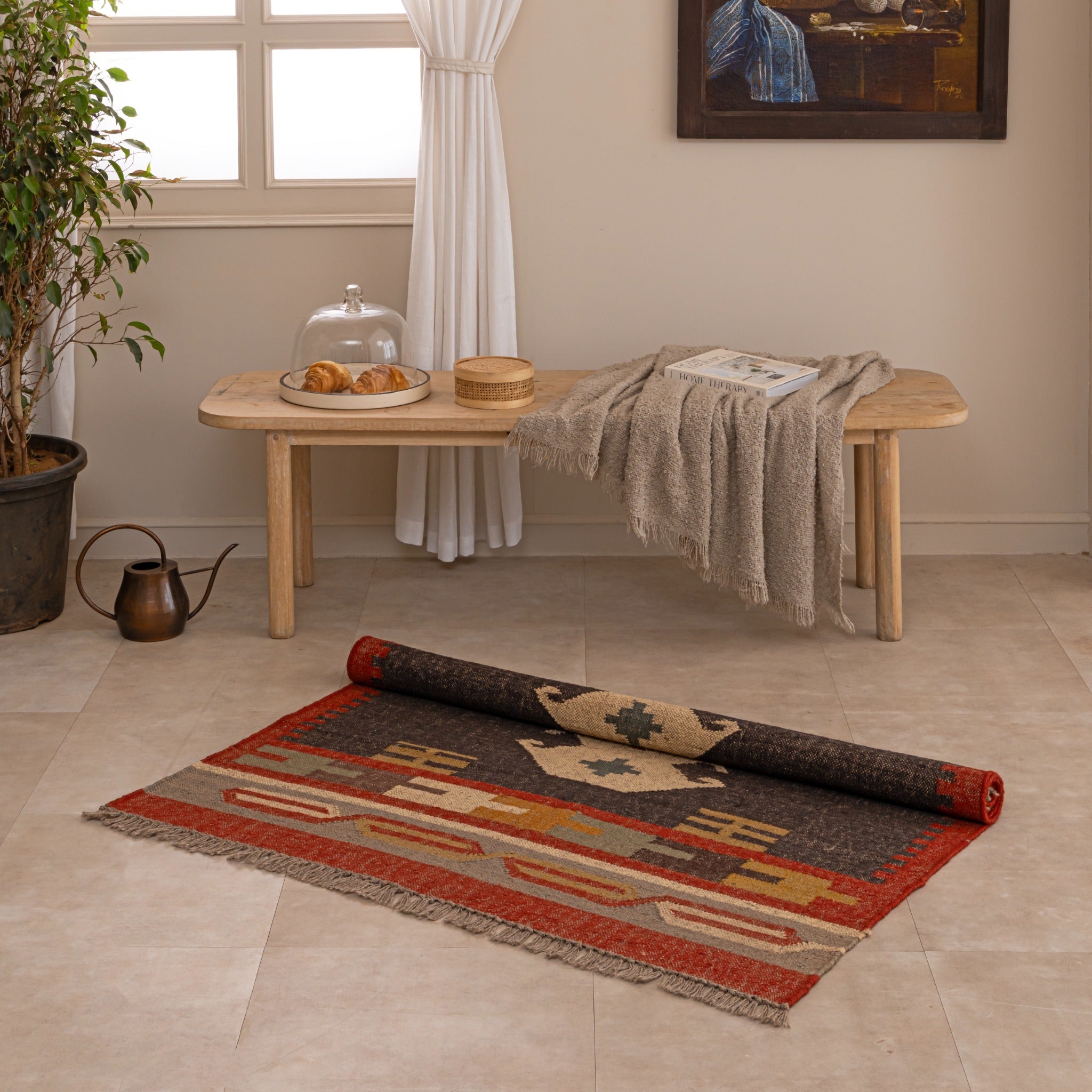 Handmade Southwestern tribal wool rug with geometric pattern in red, black, beige and mustard tones displayed in a cozy living room.
