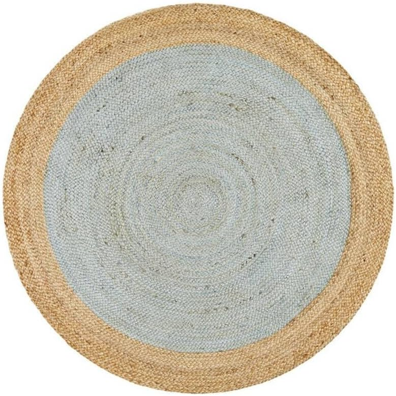 A two-tone round jute area rug featuring a muted light blue braided center and a natural tan woven border, laid on a light wood floor in a cozy coastal living room.