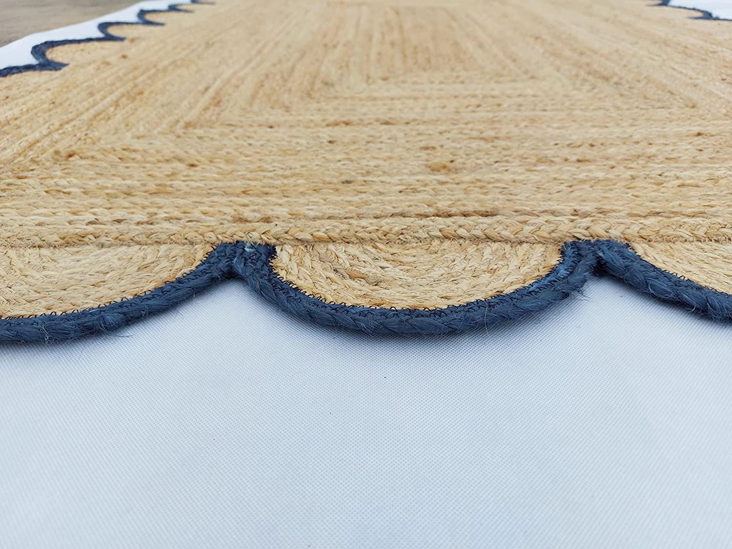 Handmade natural jute scalloped border area rug with blue trim in a bright farmhouse style living room.