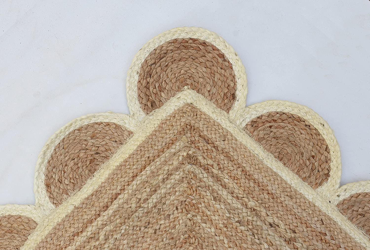 Handwoven natural jute scalloped rectangular area rug with ivory border styled in a modern Scandinavian living room.
