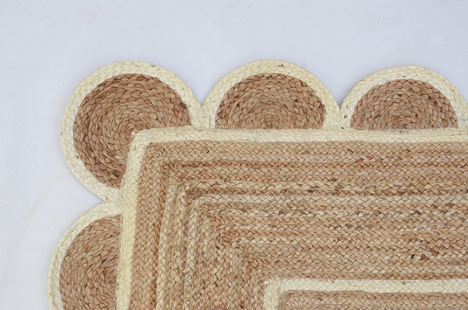 Handwoven natural jute scalloped rectangular area rug with ivory border styled in a modern Scandinavian living room.