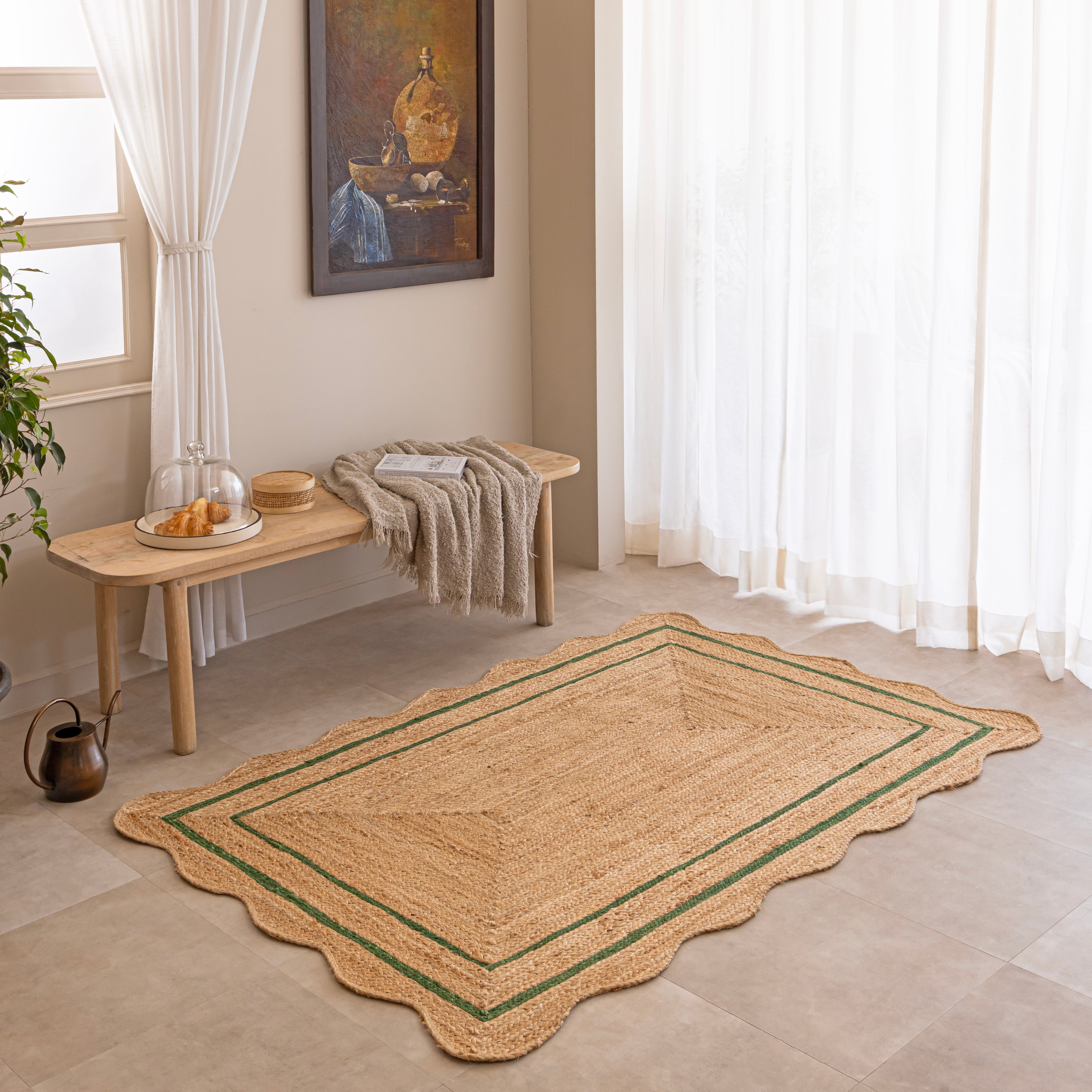 Handwoven natural jute area rug with green double border, styled in a cozy modern living room with neutral home decor.