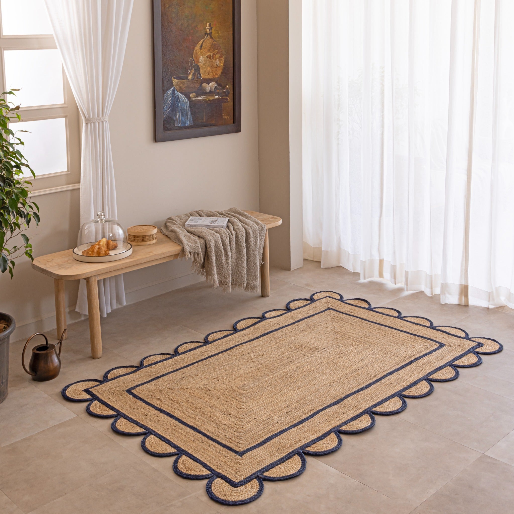 Handmade natural jute area rug with navy blue scalloped braided border in a cozy modern living room.