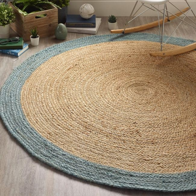 Handmade round natural jute braided rug with soft blue cotton border in a bright modern coastal living room interior