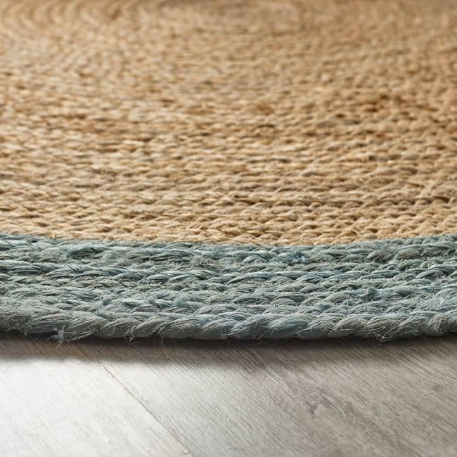Handmade round natural jute braided rug with soft blue cotton border in a bright modern coastal living room interior