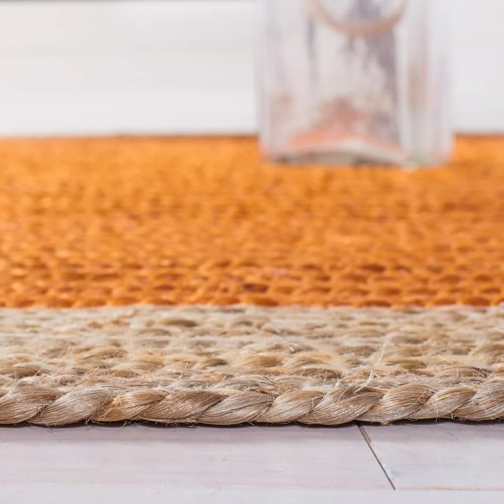 Handmade orange and natural jute round braided rug in a cozy boho living room with wooden coffee table and neutral sofa.