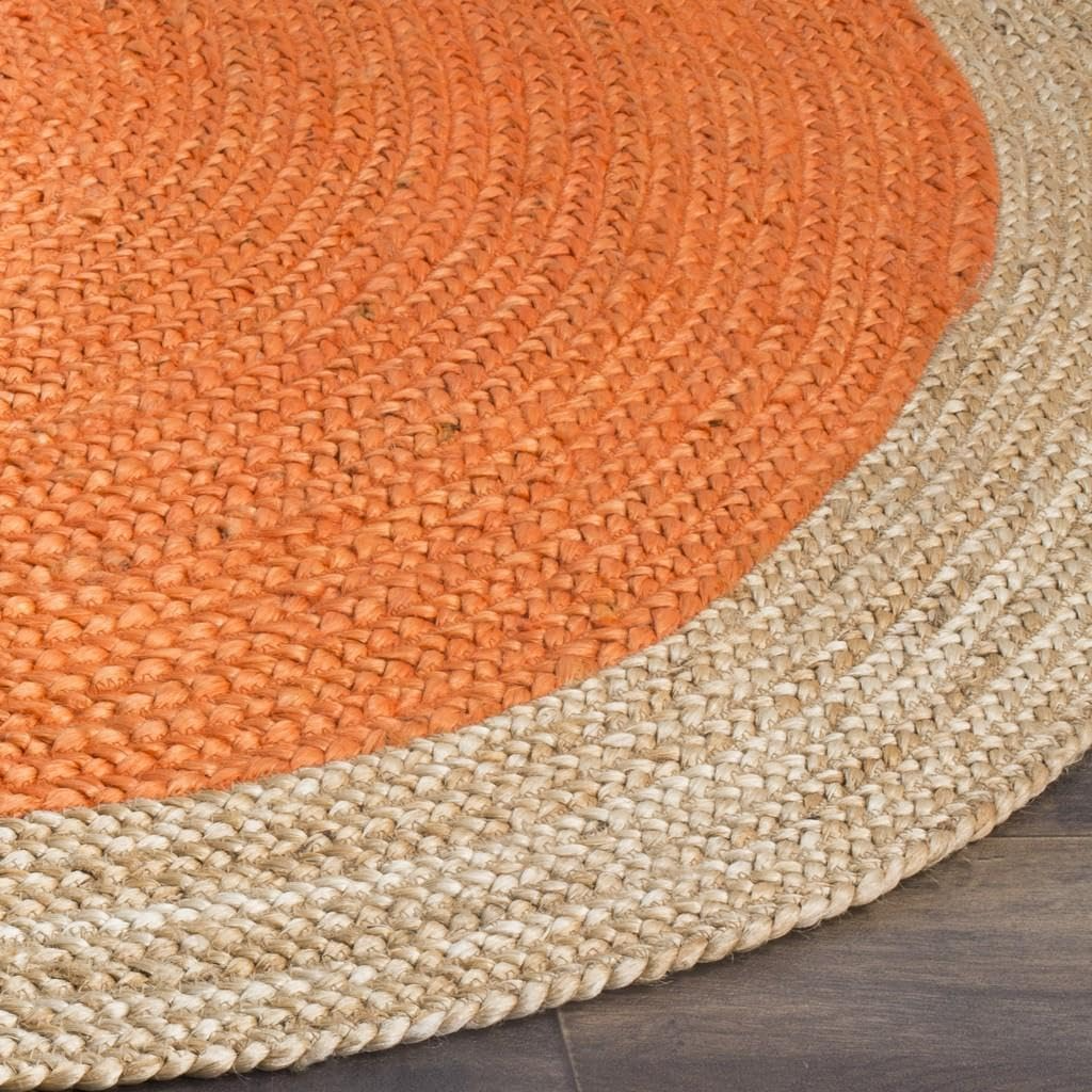 Handmade orange and natural jute round braided rug in a cozy boho living room with wooden coffee table and neutral sofa.