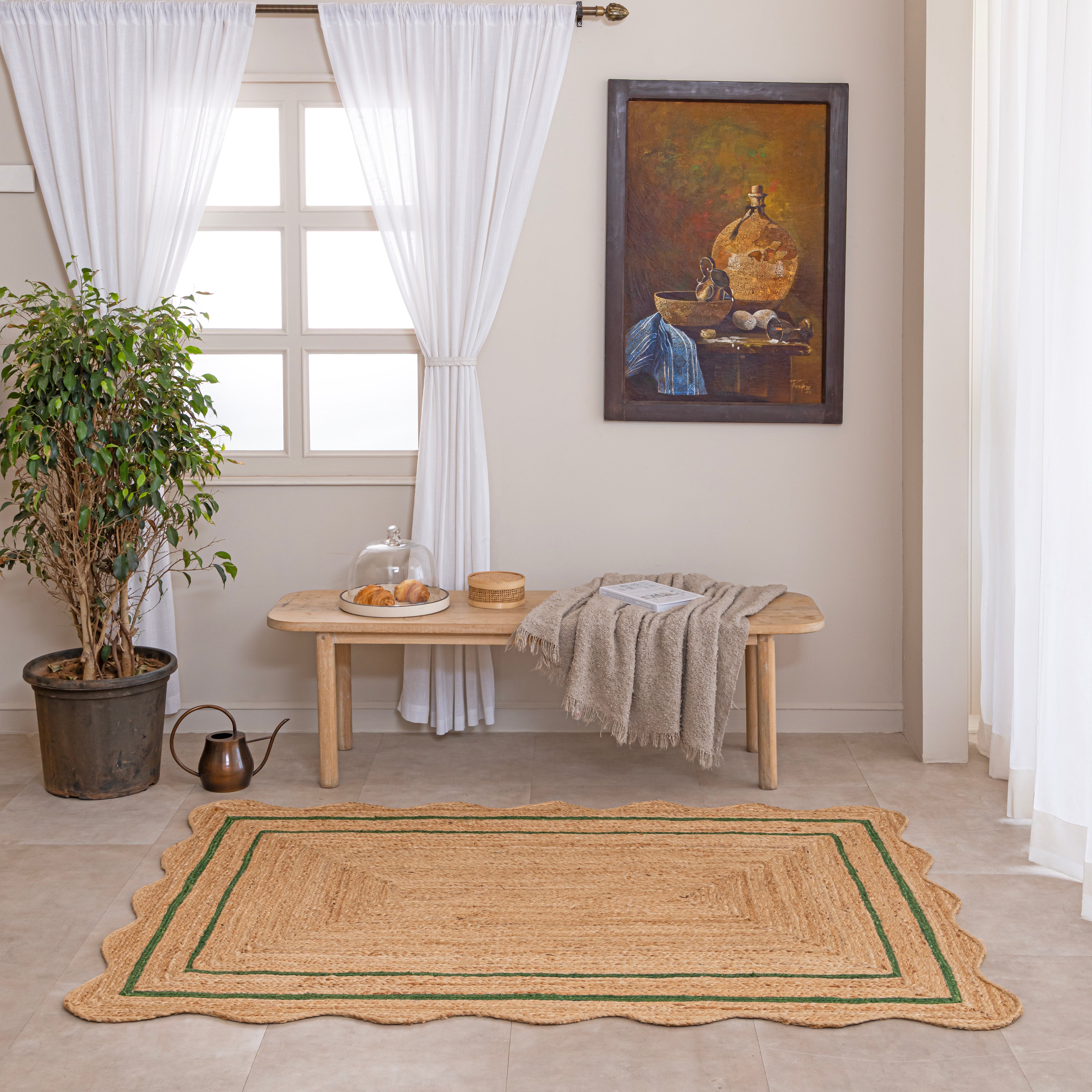 Handwoven natural jute area rug with green double border, styled in a cozy modern living room with neutral home decor.