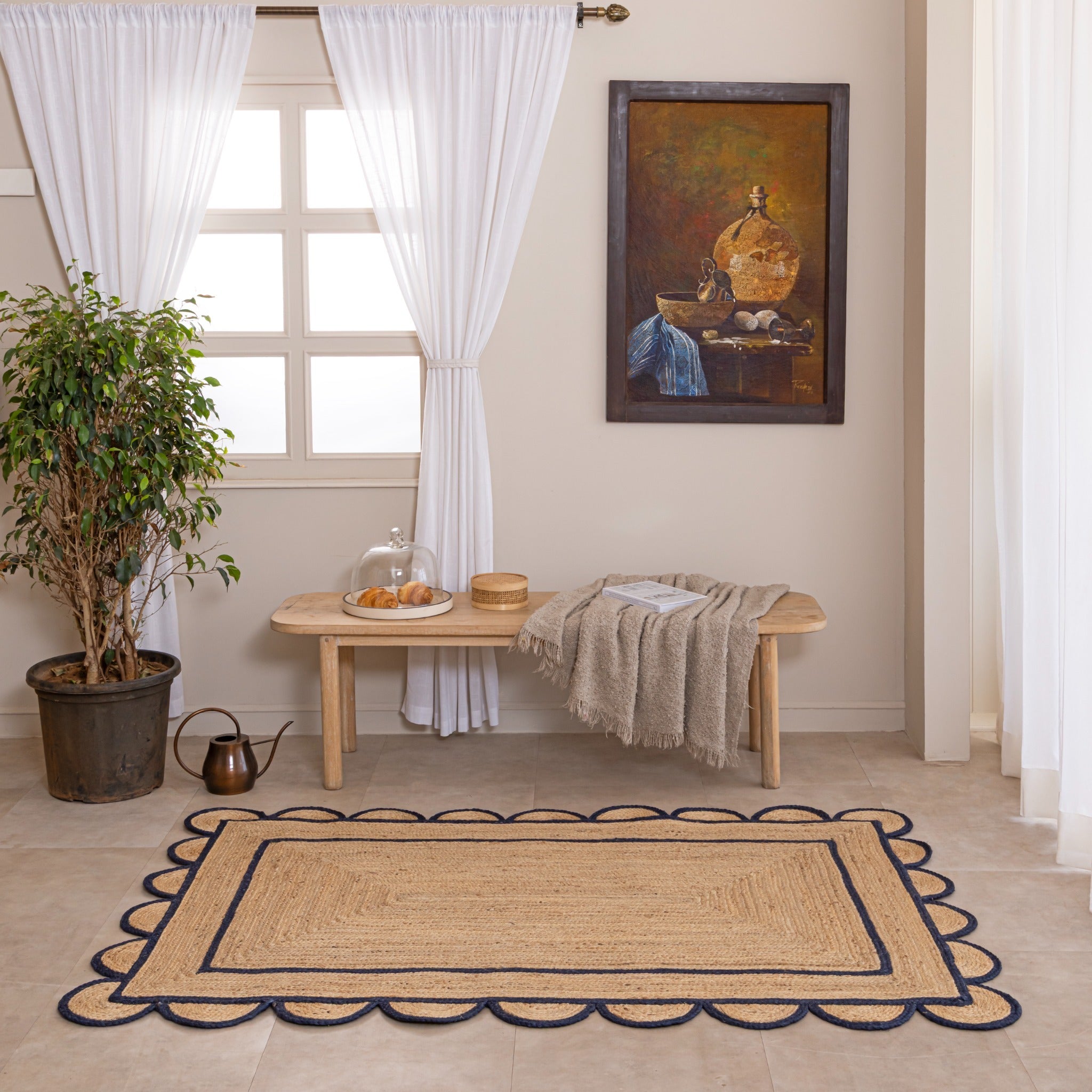 Handmade natural jute area rug with navy blue scalloped braided border in a cozy modern living room.