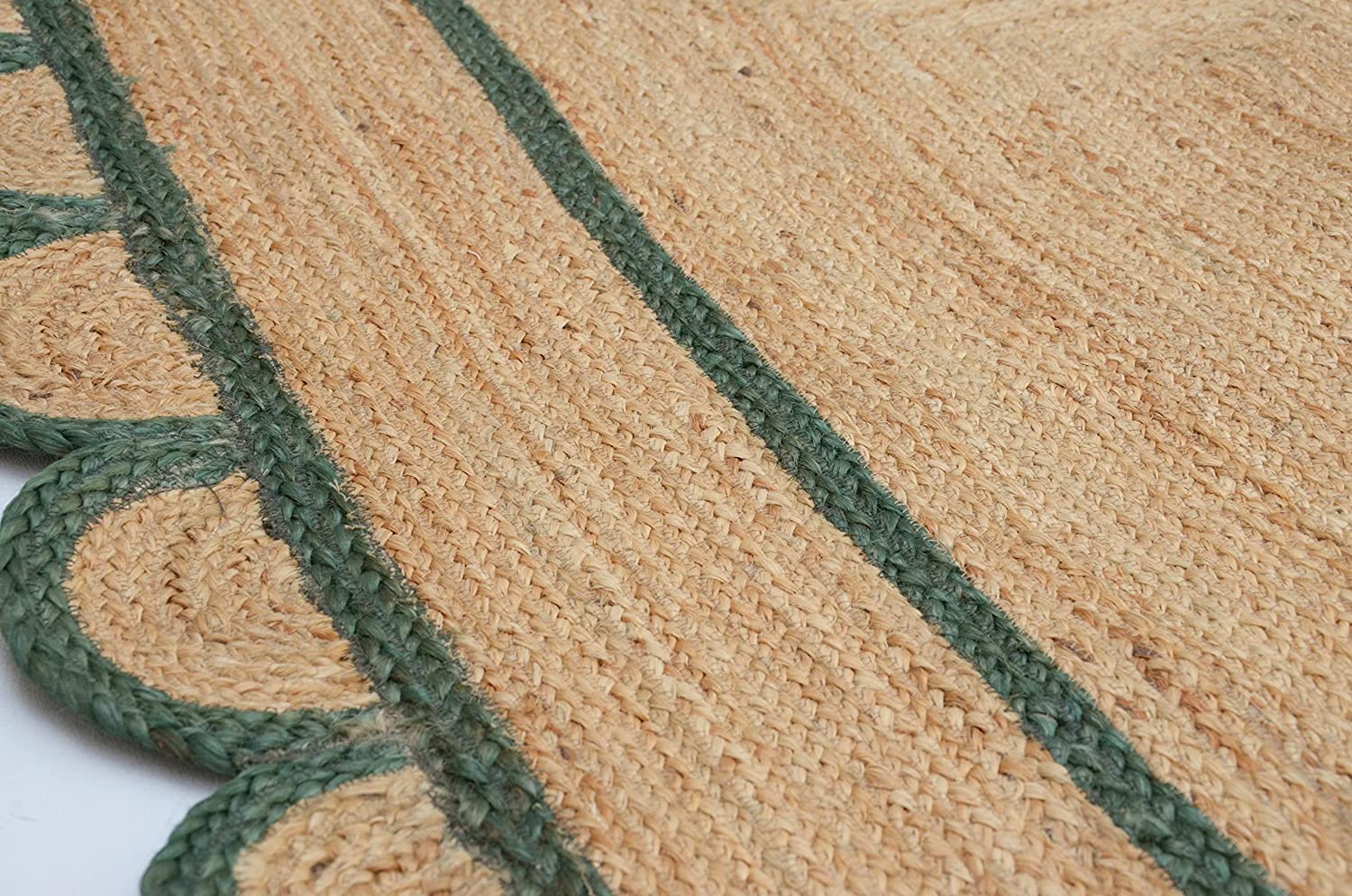 Handwoven natural jute area rug with green scalloped border placed in a modern Scandinavian living room featuring sustainable eco-friendly braided craftsmanship.