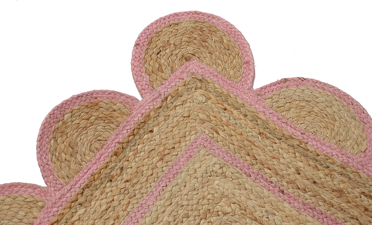 Handwoven natural jute area rug with soft pink scalloped border styled in a modern Scandinavian living room with cream sofa and wooden flooring.
