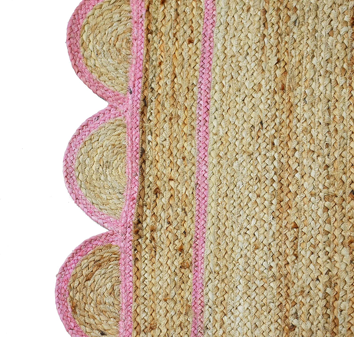 Handwoven natural jute area rug with soft pink scalloped border styled in a modern Scandinavian living room with cream sofa and wooden flooring.