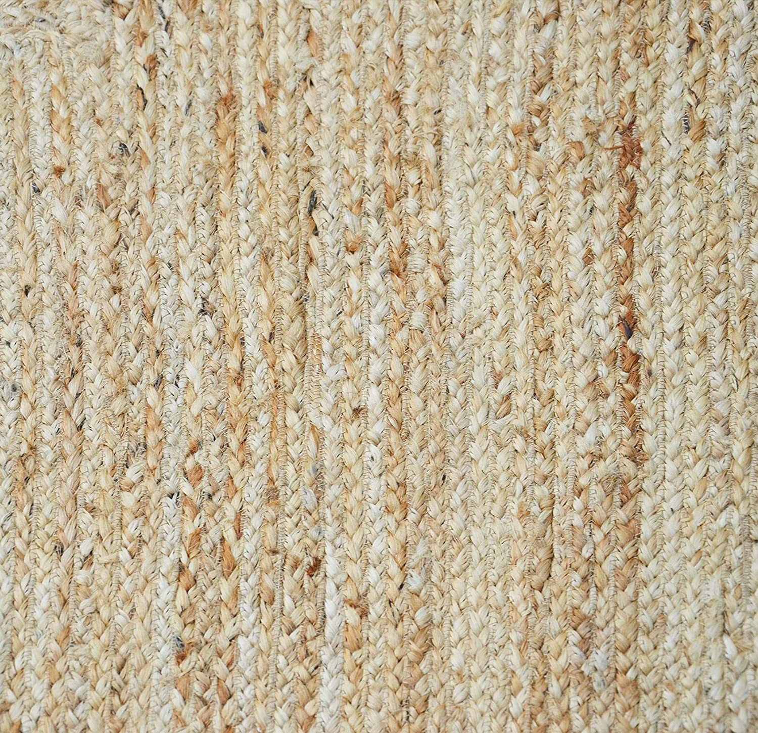 Handwoven natural jute area rug with soft pink scalloped border styled in a modern Scandinavian living room with cream sofa and wooden flooring.