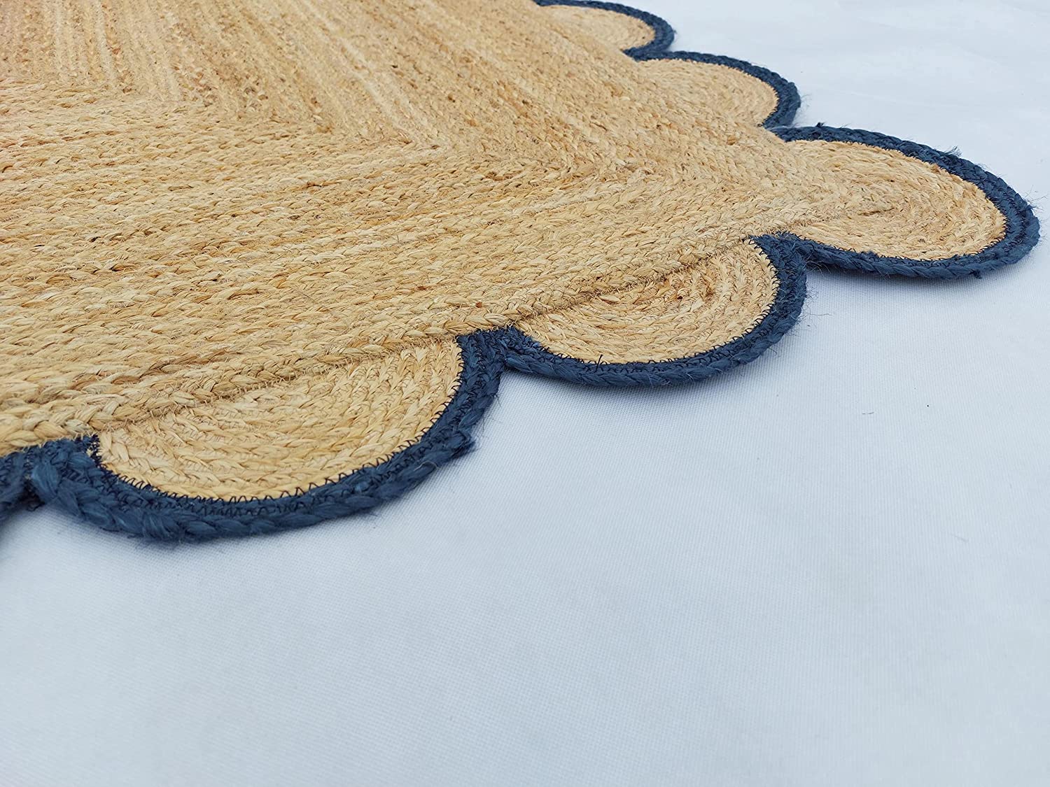 Handmade natural jute scalloped border area rug with blue trim in a bright farmhouse style living room.