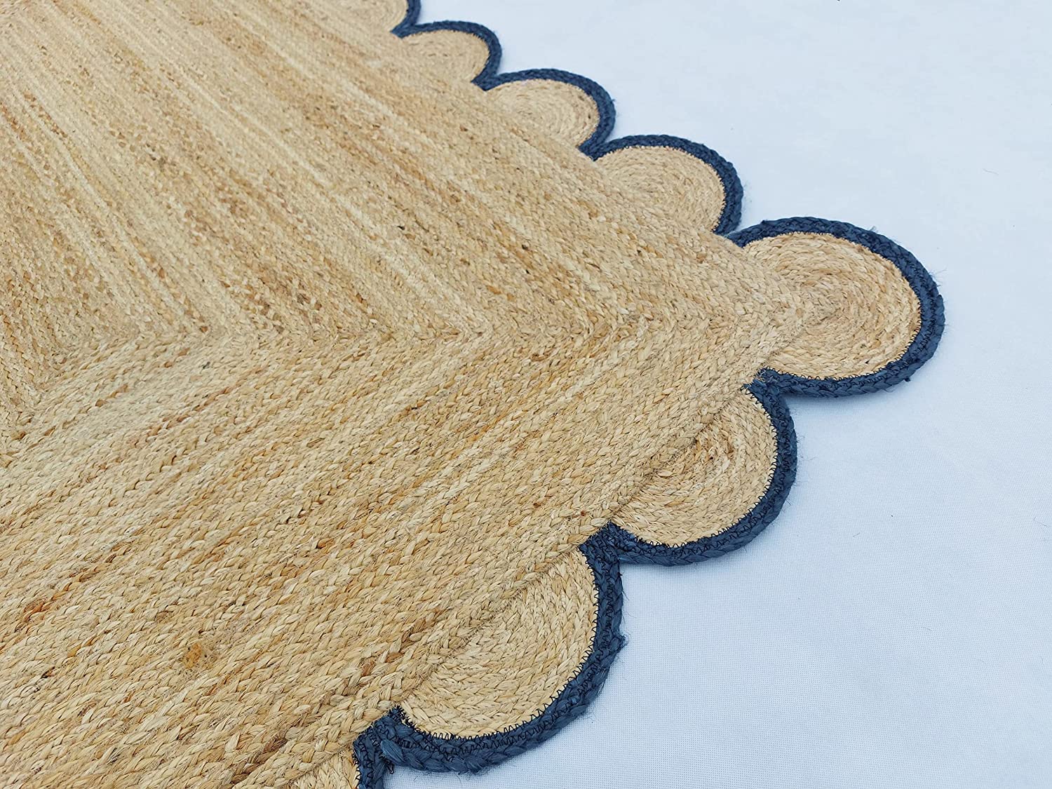 Handmade natural jute scalloped border area rug with blue trim in a bright farmhouse style living room.