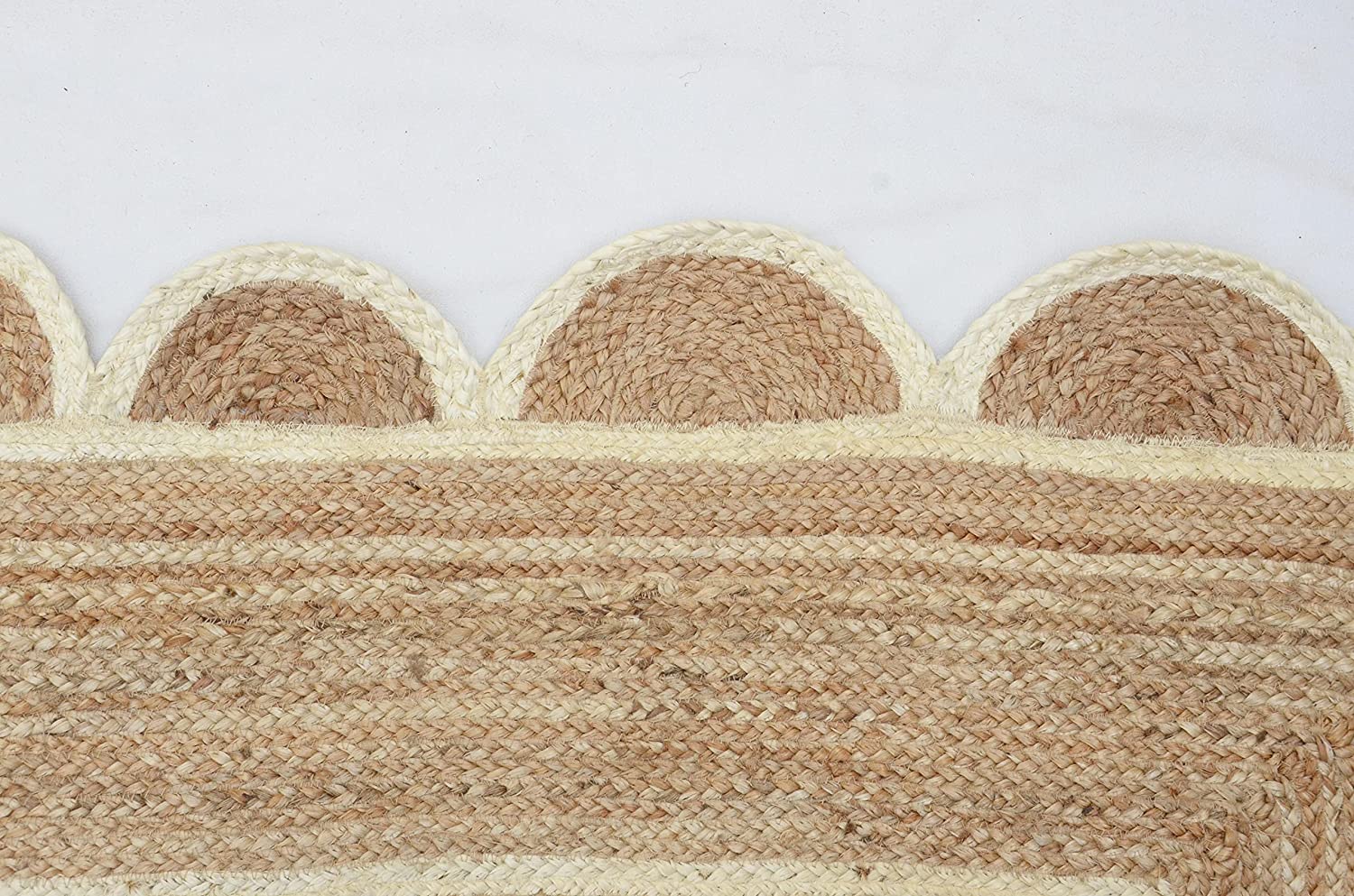 Handwoven natural jute scalloped rectangular area rug with ivory border styled in a modern Scandinavian living room.