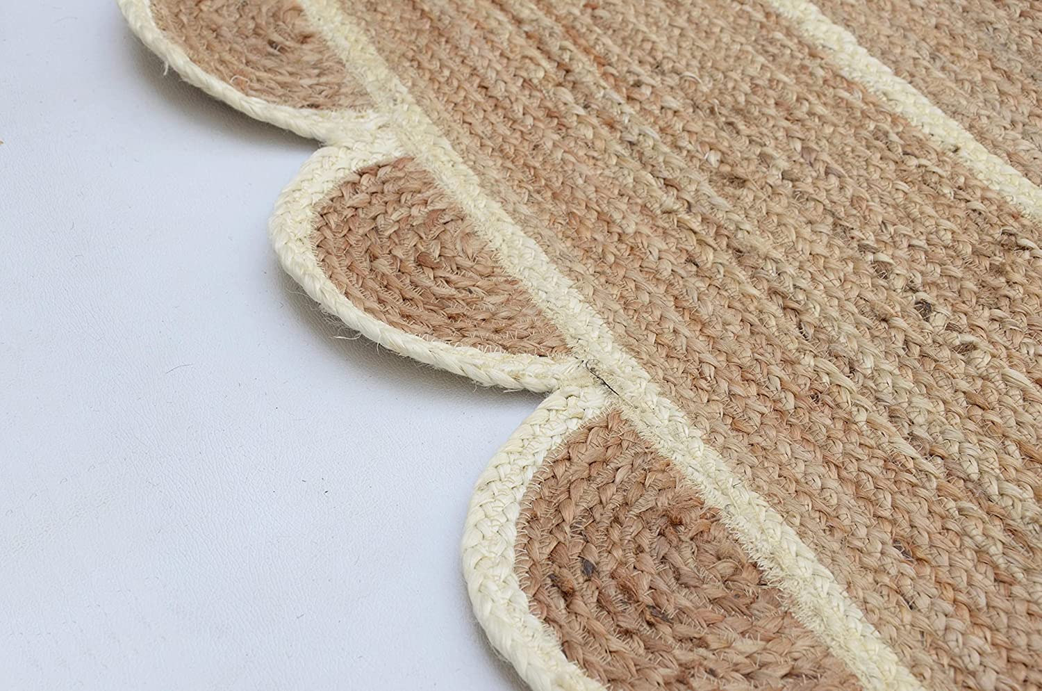 Handwoven natural jute scalloped rectangular area rug with ivory border styled in a modern Scandinavian living room.
