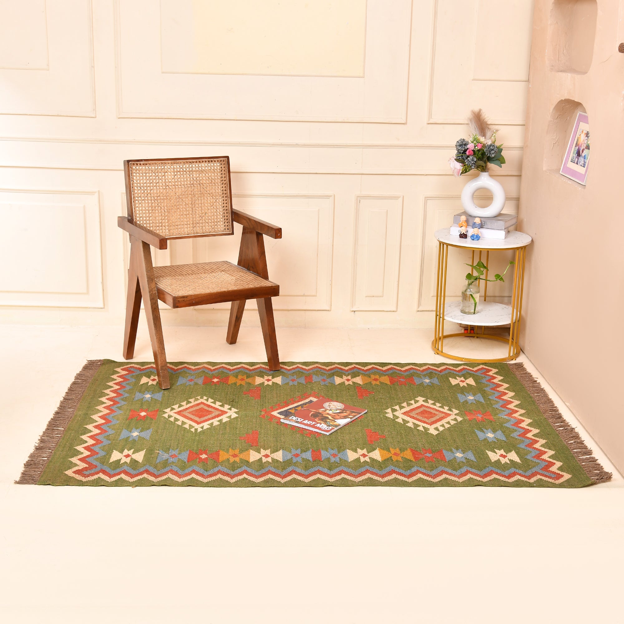 Handwoven Green Kilim Area Rug with colorful tribal geometric pattern made from wool and cotton, styled in a modern living room with wooden chair and side table.