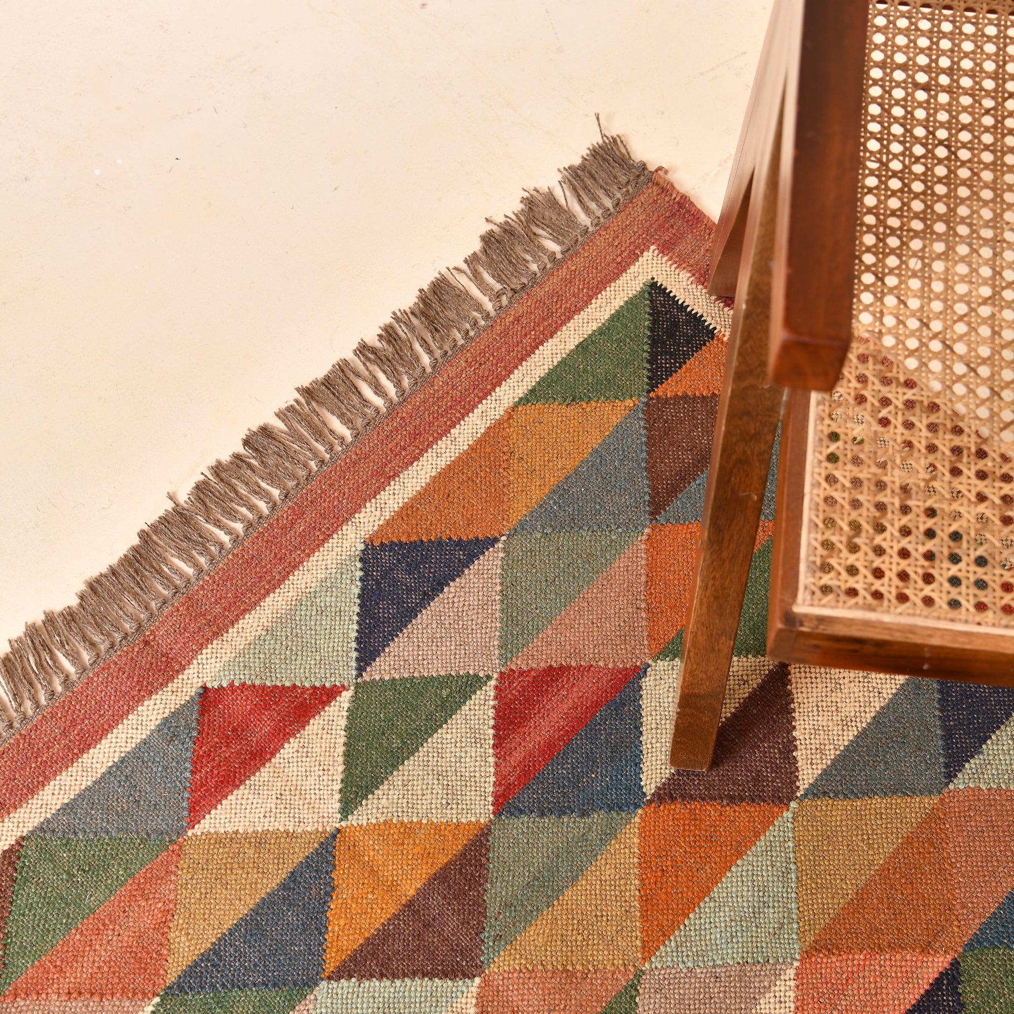 Handwoven terracotta diamond Kilim area rug with geometric tribal design, handmade from wool and cotton, styled in a modern living room with a wooden accent chair and side table.