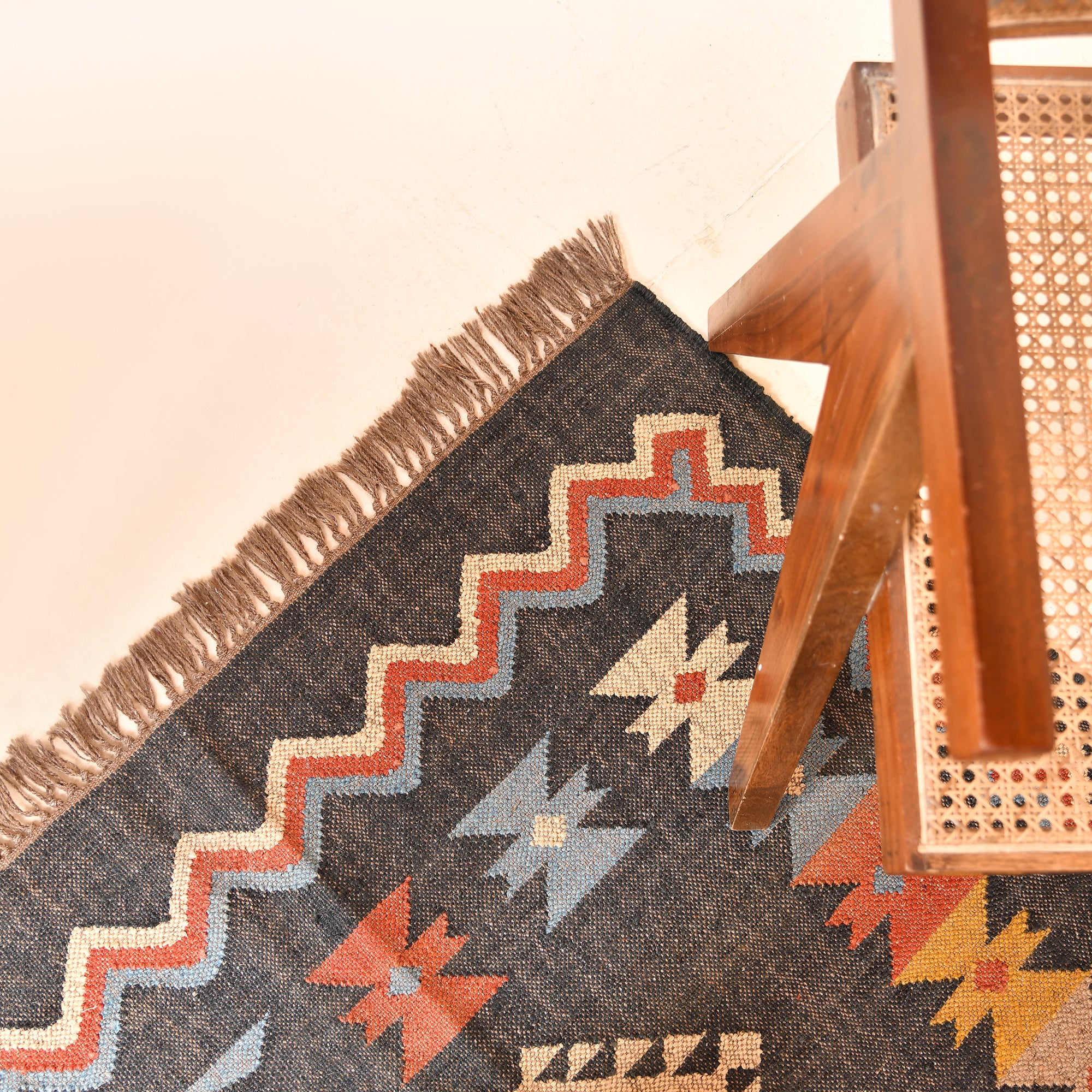 Handwoven charcoal grey wool and jute Southwestern tribal flatweave area rug with colorful geometric pattern.