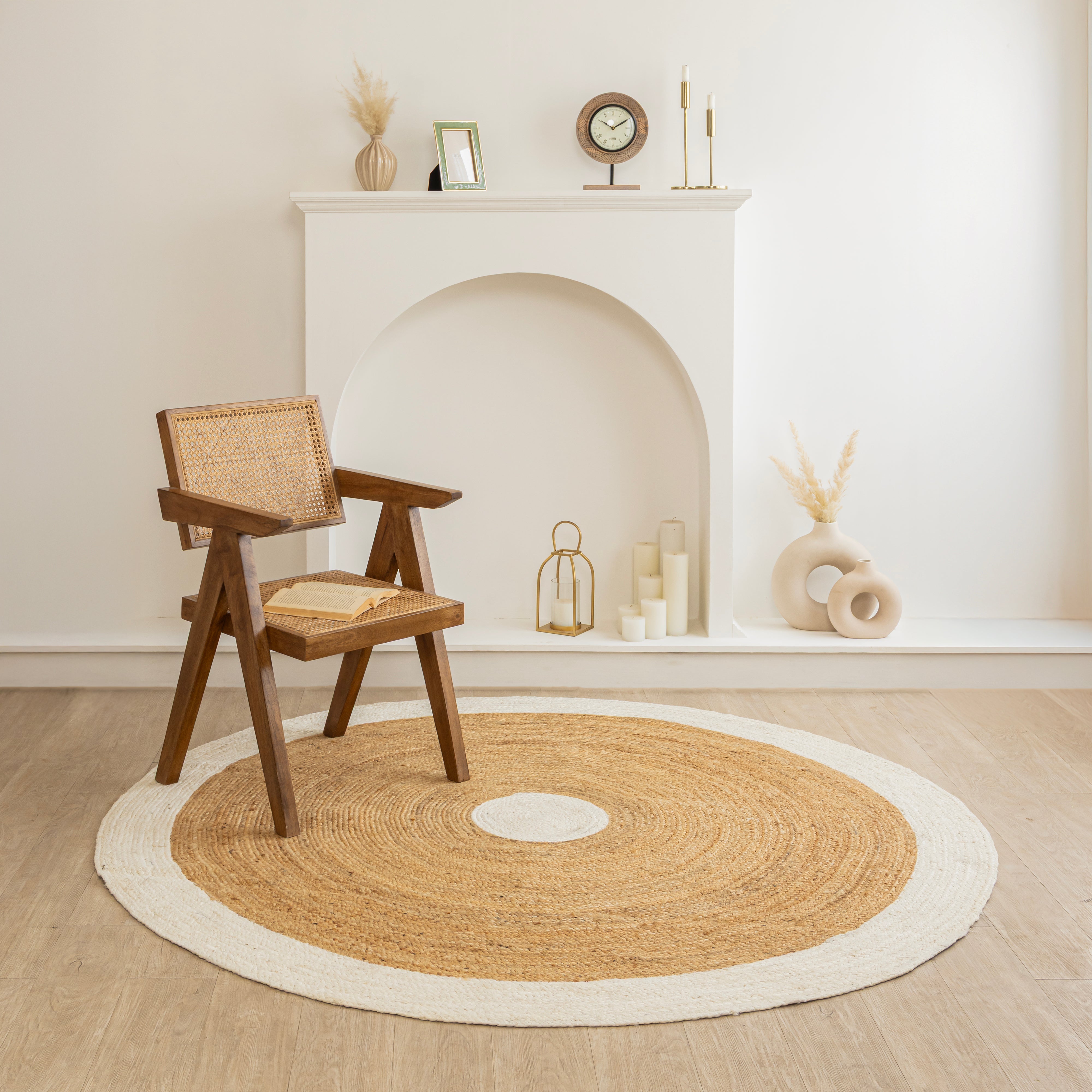 Handwoven round natural jute rug with white border placed in a modern living room featuring a wooden chair and minimalist home décor.