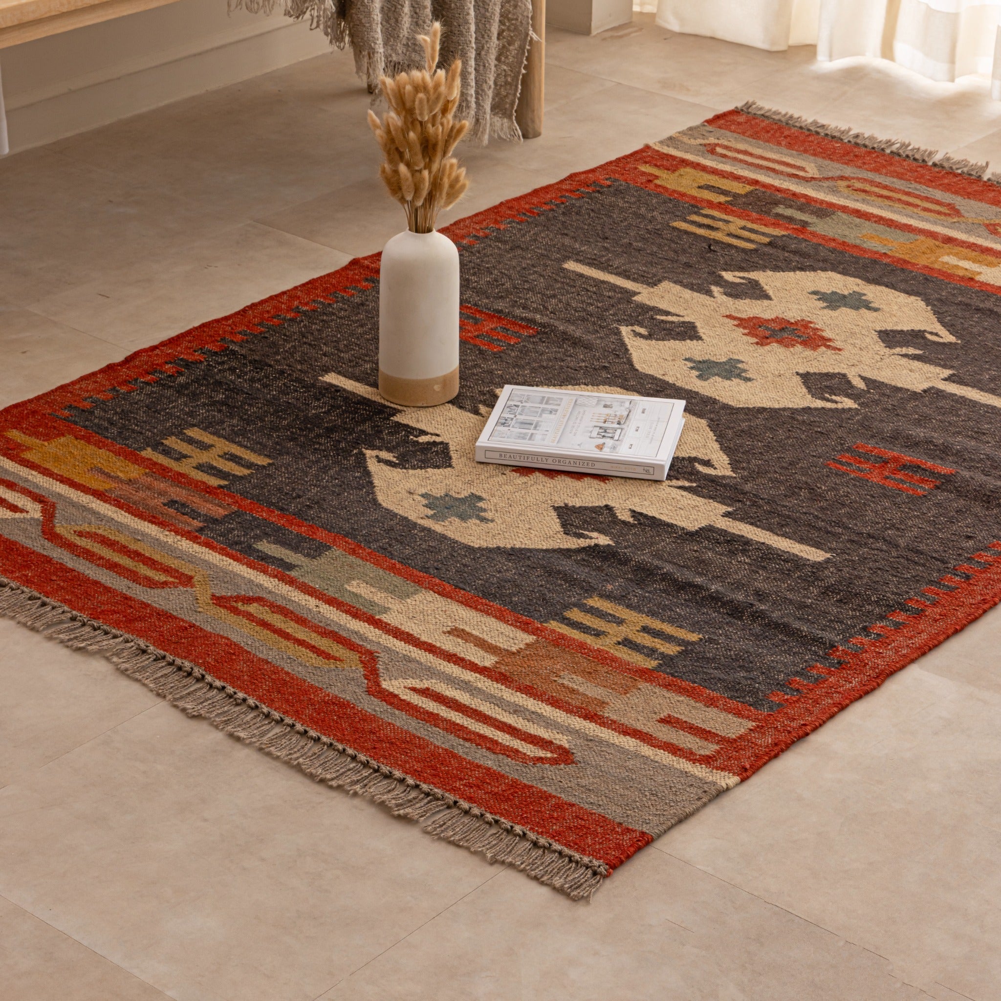 Handmade Southwestern tribal wool rug with geometric pattern in red, black, beige and mustard tones displayed in a cozy living room.