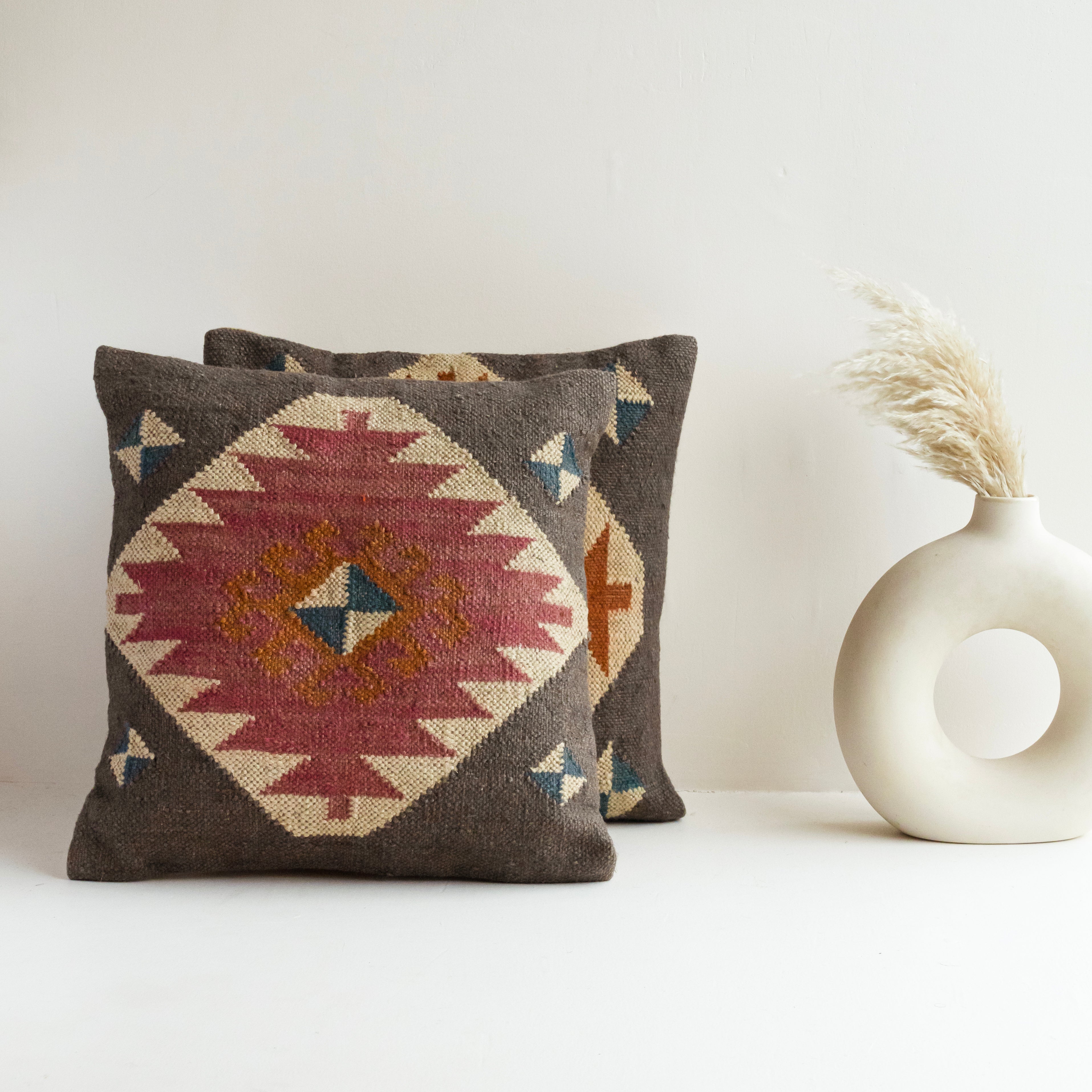 Handwoven gray Kilim wool cushion cover with a pink geometric tribal medallion, handmade decorative throw pillow for boho, farmhouse, rustic, and Southwestern home décor.
