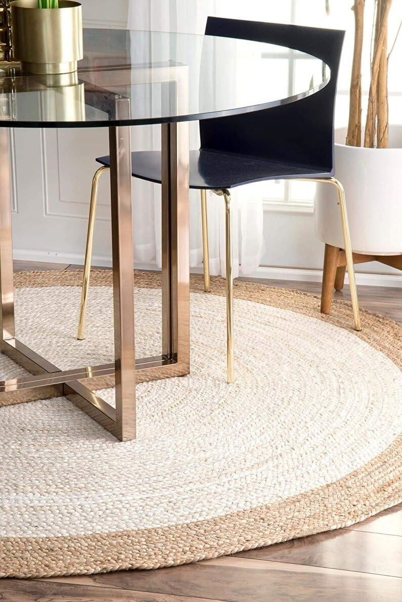 Handmade natural jute and ivory round rug with braided texture in a cozy neutral boho living room with a wooden coffee table and beige sofa.