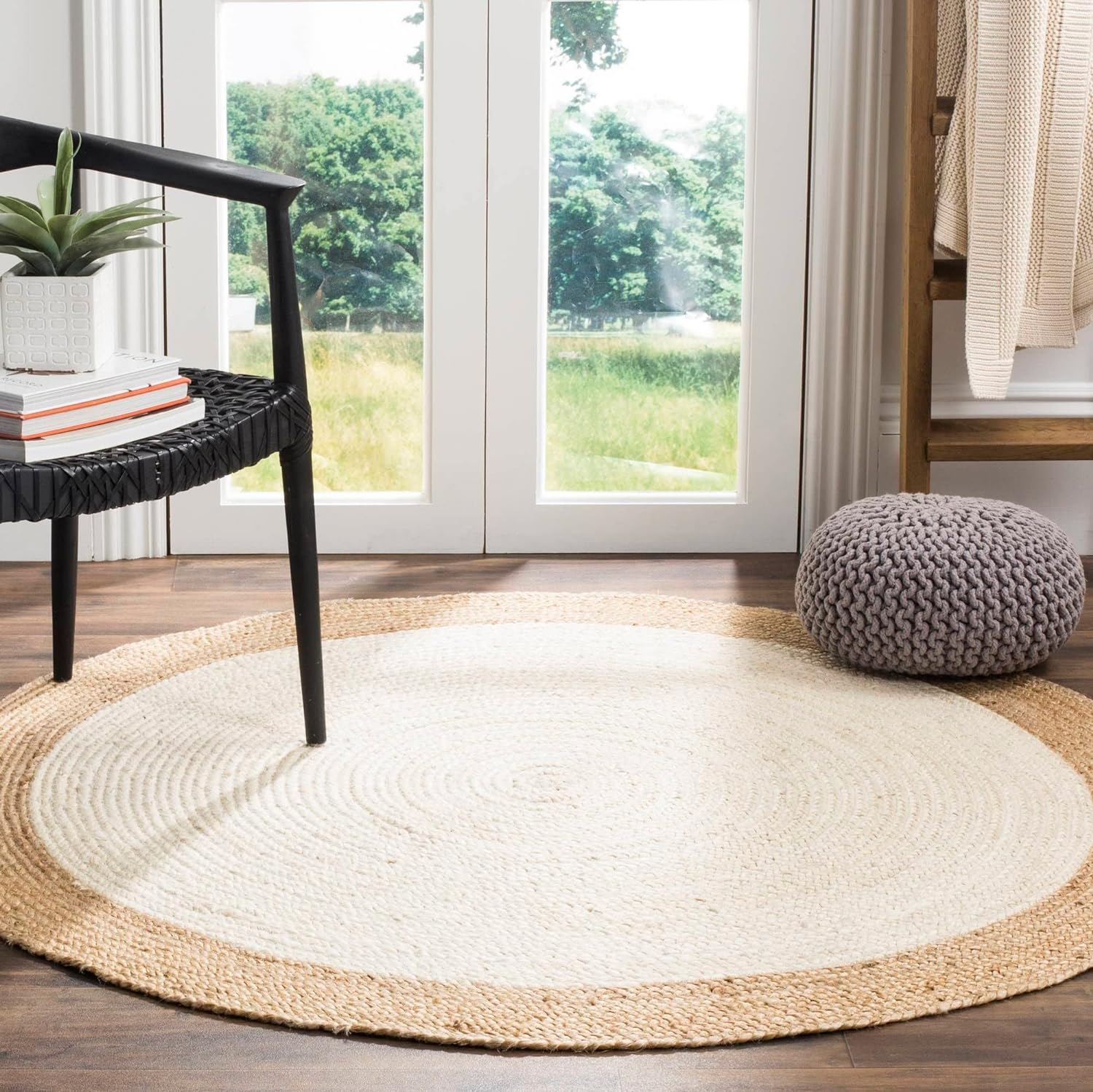 Handmade natural jute and ivory round rug with braided texture in a cozy neutral boho living room with a wooden coffee table and beige sofa.