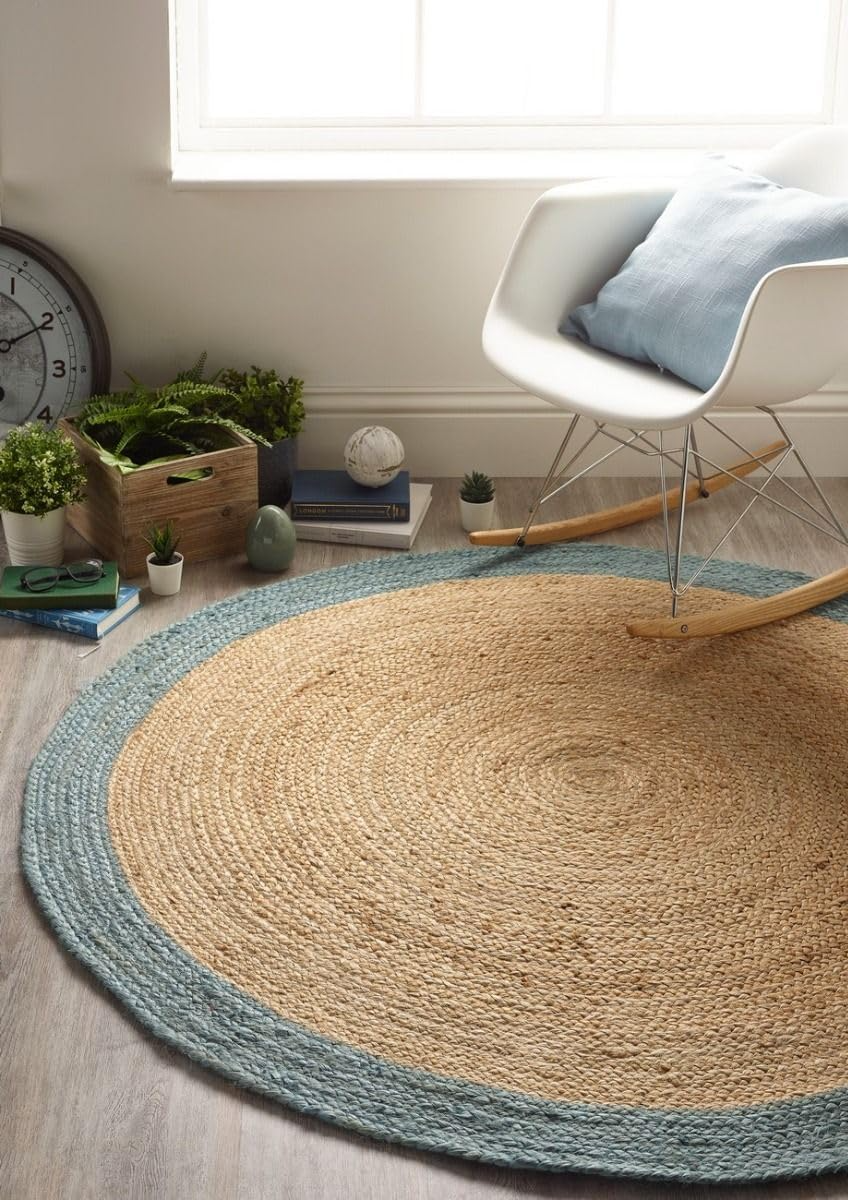 Handmade round natural jute braided rug with soft blue cotton border in a bright modern coastal living room interior