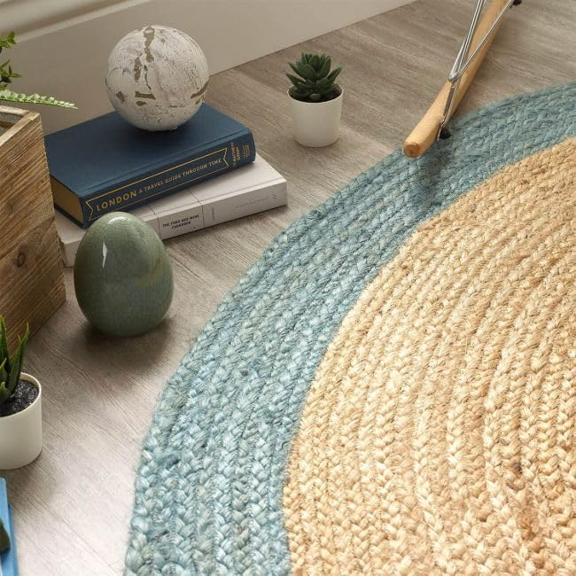 Handmade round natural jute braided rug with soft blue cotton border in a bright modern coastal living room interior