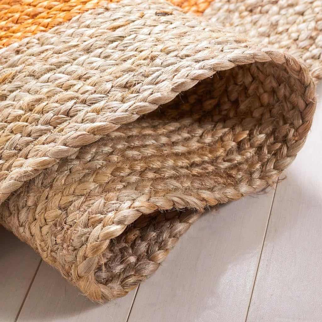 Handmade orange and natural jute round braided rug in a cozy boho living room with wooden coffee table and neutral sofa.